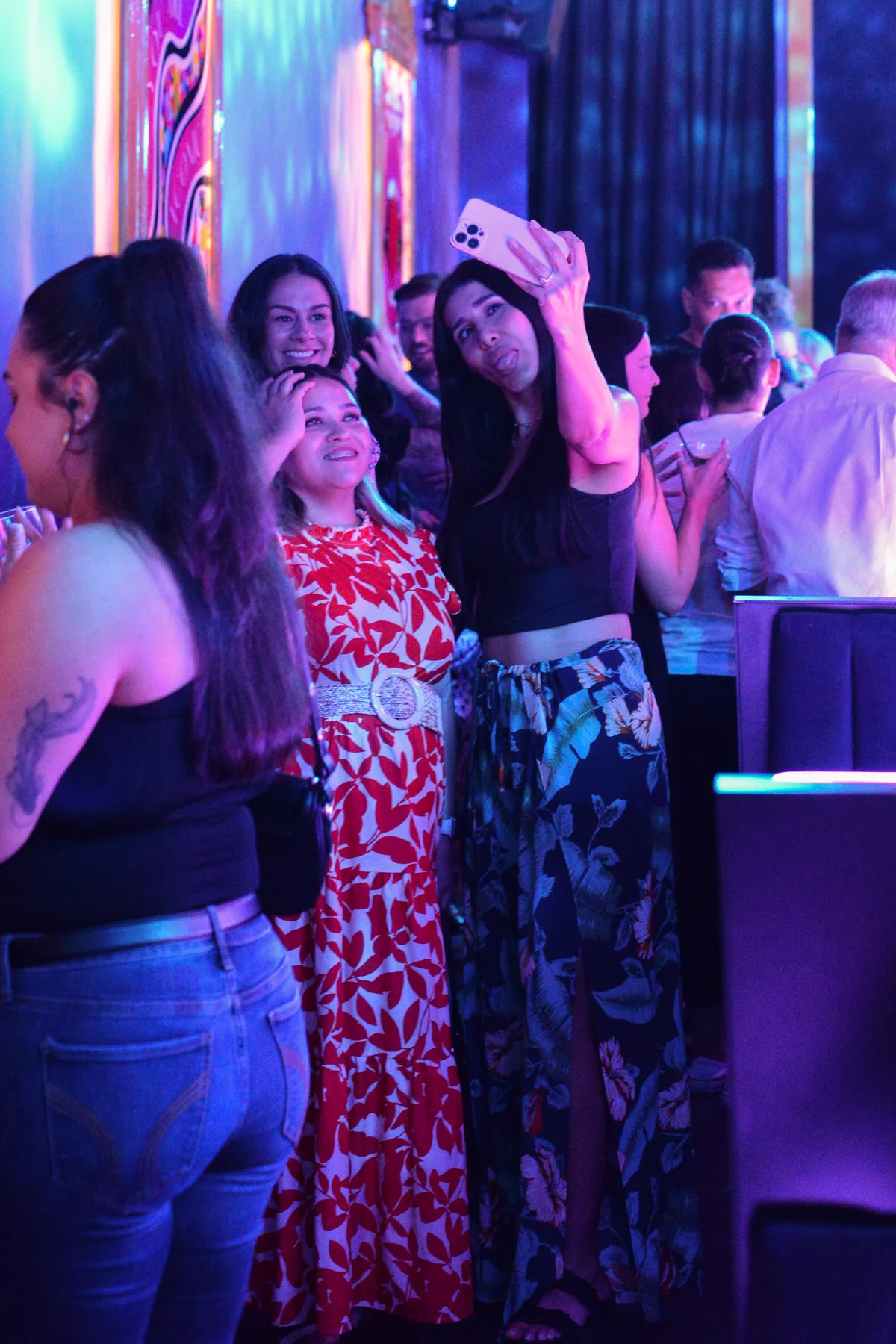 Friends taking a photo together beneath Lola’s colorful lights